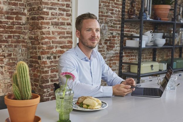 Man sitting at kitchen table with laptop