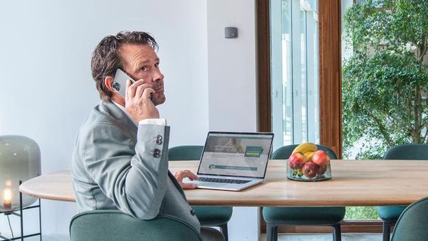 man achter laptop aan het telefoneren