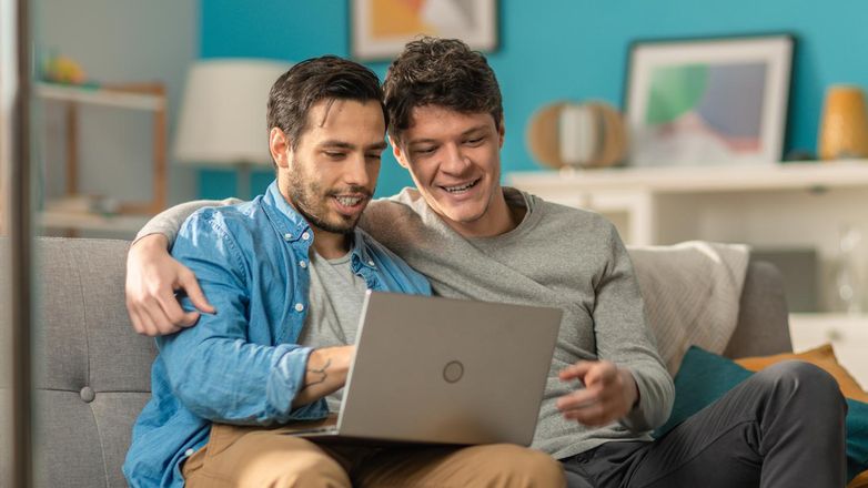 Two men on the couch looking at laptop