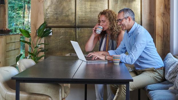 Man en vrouw aan tafel kijkend naar laptop