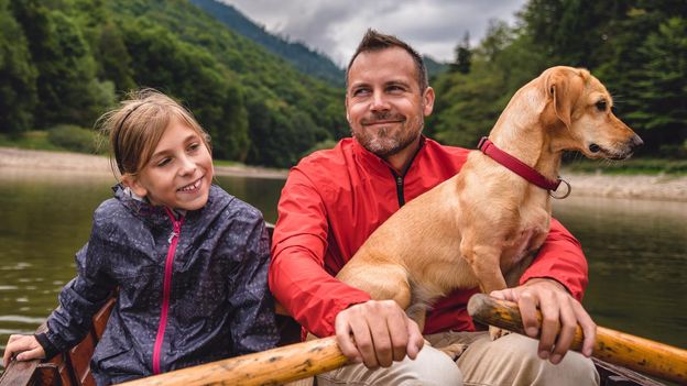 Vader en dochter met hond in een boot op de rivier