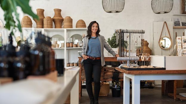 Vrouw staat in haar eigen winkel.