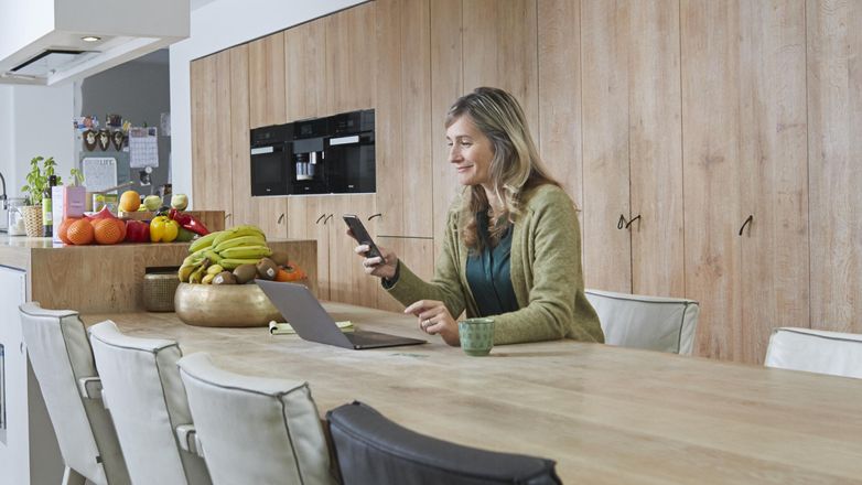 vrouw aan tafel met mobiel in handen